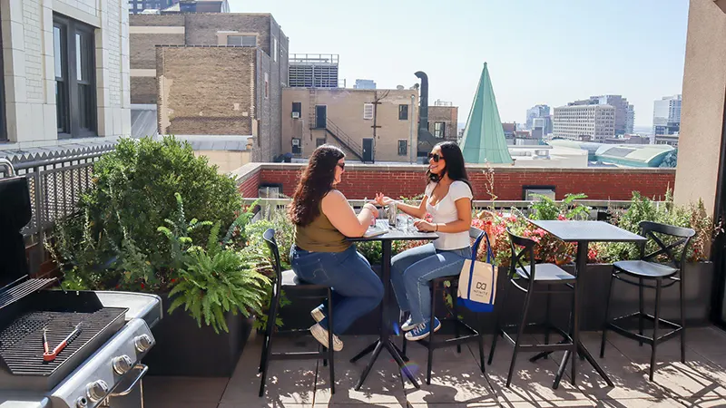 Private resident rooftop patio featuring comfortable seating and gas grills in Chicago